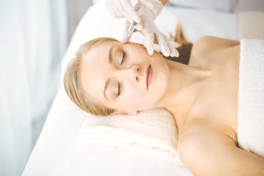 Güzellik doktoru sarışın kadın yüzüne şırıngayla güzellik prosedürü uyguluyor. Kozmetik tıp, güzellik enjeksiyonu konsepti