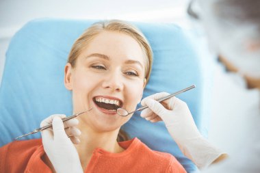 Mutlu gülümseyen kadın dişçi kliniğinde dişçi tarafından muayene ediliyor. Sağlıklı dişler ve ilaçlar, stomatoloji konsepti