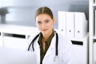Hastane ofisindeki masada otururken bilgisayar başında daktilo yazan bir doktor. Hekim kadın iş başında. Tıp ve sağlık alanlarındaki veriler