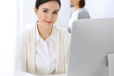 Ofiste bilgisayarla çalışan bir iş kadını, arka planda çalışan bir iş arkadaşı. Masada otururken avukatın ya da muhasebecinin vesikalığı.