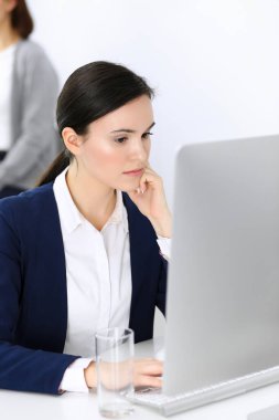Ofiste bilgisayarla çalışan bir iş kadını, arka planda çalışan bir iş arkadaşı. Masada otururken avukatın ya da muhasebecinin vesikalığı.