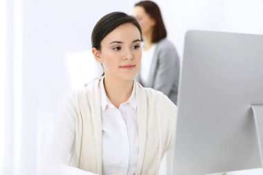 Ofiste bilgisayarla çalışan bir iş kadını, arka planda çalışan bir iş arkadaşı. Masada otururken avukatın ya da muhasebecinin vesikalığı.