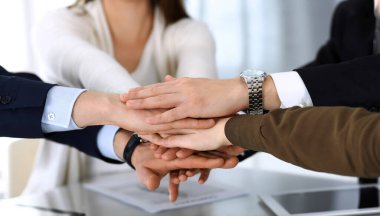 Takım çalışması yapan ve el ele tutuşan iş adamları grubu ya da modern ofiste kontrat imzaladıktan sonra beş kişi. Meslektaşları ya da avukatları olan tanınmamış işadamı ve kadın elleriyle daire çiziyor.