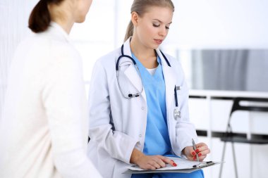 Muayene sırasında doktor ve hasta. Acil serviste portre çekimi yaparken ilaç geçmişini dolduran bir doktor. İlaç ve sağlık hizmetleri kavramı