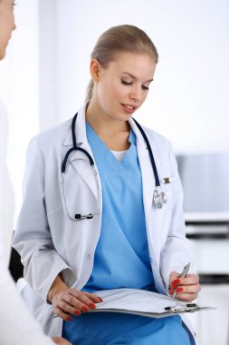 Muayene sırasında doktor ve hasta. Acil serviste portre çekimi yaparken ilaç geçmişini dolduran bir doktor. İlaç ve sağlık hizmetleri kavramı