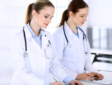 Hastanede çalışan bir grup doktor. Doktor resepsiyonda beklerken tıbbi belge ya da reçete dolduruyor. Tıp ve sağlık hizmetleri kavramındaki veriler