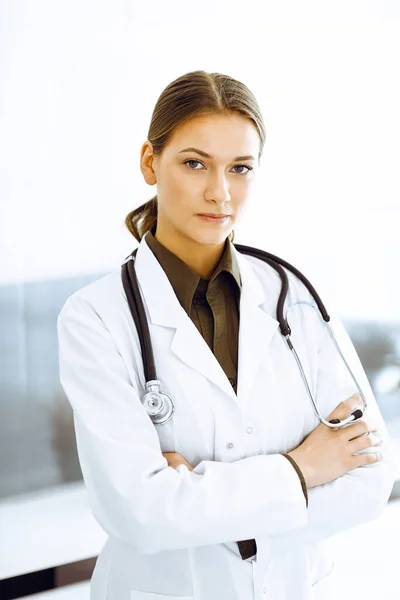 Donna-medico in piedi con le braccia incrociate e guardando la macchina fotografica. Servizio medico perfetto in clinica — Foto Stock