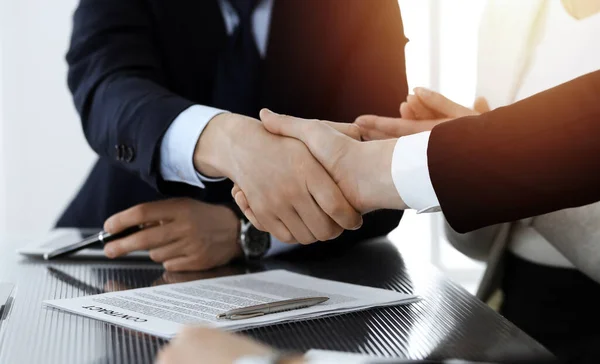 Zakenmensen schudden elkaar de hand na het tekenen van een contract in het zonnige moderne kantoor. Teamwork en handdruk concept — Stockfoto