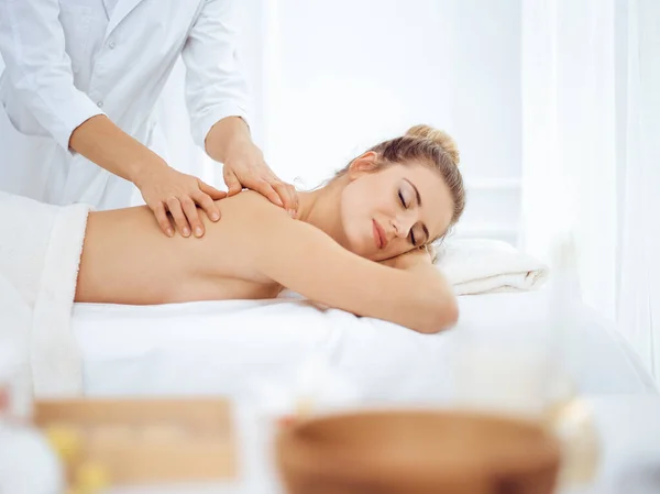 Jeune femme blonde profitant d'un massage du dos dans un salon de spa. Concept de beauté — Photo