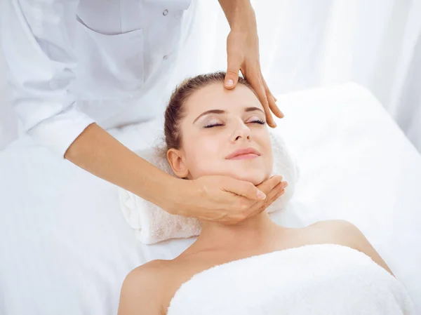 Mujer joven y rubia disfrutando de masajes faciales en el salón de spa. Concepto de belleza — Foto de Stock