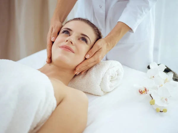 Jonge en blonde vrouw geniet van gezichtsmassage in spa salon. Schoonheidsconcept — Stockfoto