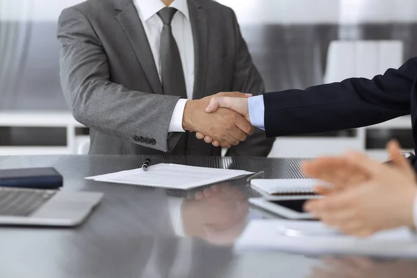 Unknown business people are shaking hands after contract signing in modern office, close-up. Handshake as successful negotiation ending