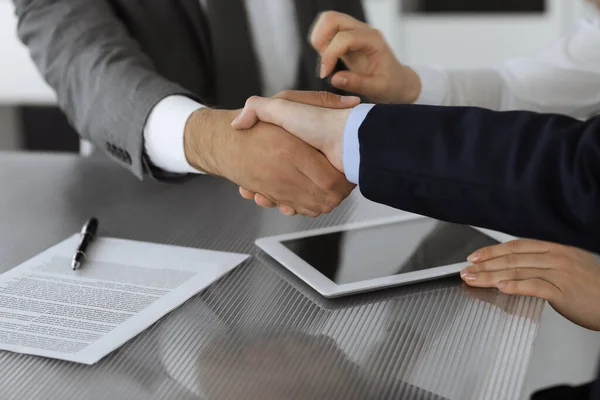Handshake as successful negotiation ending, close-up. Unknown business people shaking hands after contract signing in modern office