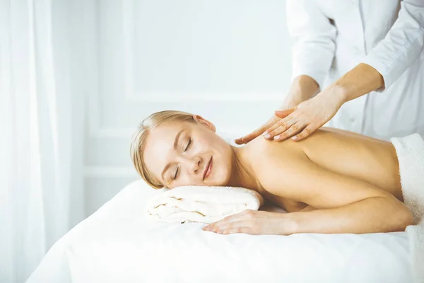 Beautiful happy woman enjoying back massage with closed eyes. Beauty and Spa salon concept — Stock Photo, Image