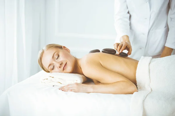 Beautiful happy woman enjoying warm stones procedure with closed eyes. Beauty and Spa salon concept — Stock Photo, Image