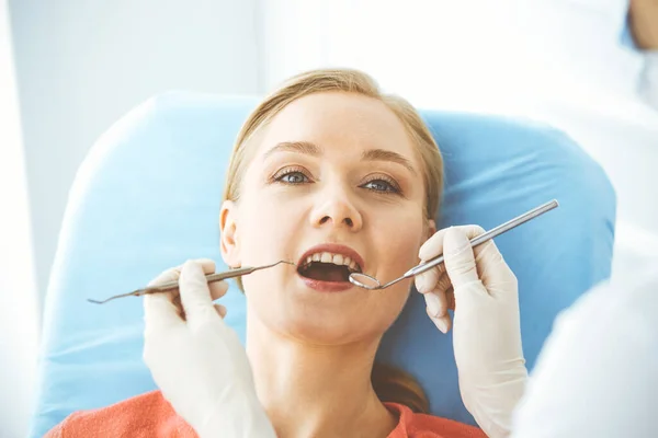 Happy smiling woman is being examined by dentist at dental clinic. Healthy teeth and medicine, stomatology concept — Stock Photo, Image