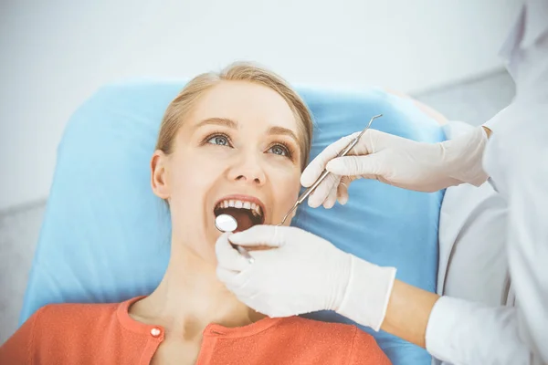 Szczęśliwa uśmiechnięta kobieta jest badana przez dentystę w klinice dentystycznej. Zdrowe zęby i medycyna, koncepcja stomatologii — Zdjęcie stockowe