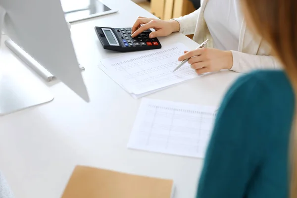 Contador que comprueba el estado financiero o cuenta por la renta de la calculadora para el formulario de impuestos, manos de cerca. Mujer de negocios sentada y trabajando con un colega en el escritorio de la oficina. Concepto de auditoría — Foto de Stock