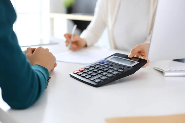 A könyvelő ellenőrzi a pénzügyi kimutatást, vagy számológép bevételével számolja az adóbevallást, kezek közelről. Üzletasszony ül és dolgozik a kollégájával az irodában. Ellenőrzési koncepció — Stock Fotó