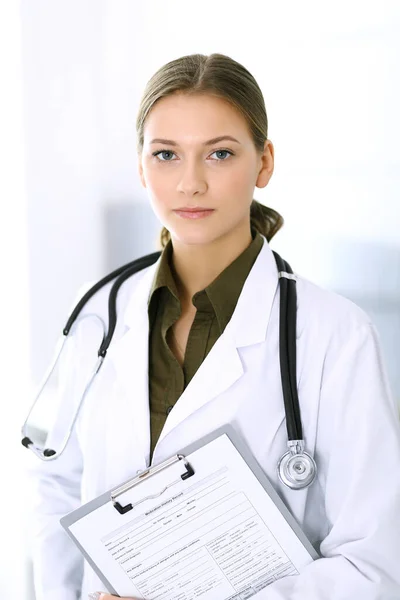 Doctora de pie recta y mirando a la cámara. Servicio médico perfecto en la clínica. Futuro feliz en medicina y salud — Foto de Stock