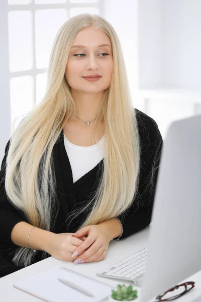 Mujer de negocios rubia sentada y trabajando con computadora en oficina blanca. Estudiante chica estudiando o secretaria haciendo informe. Concepto de éxito — Foto de Stock