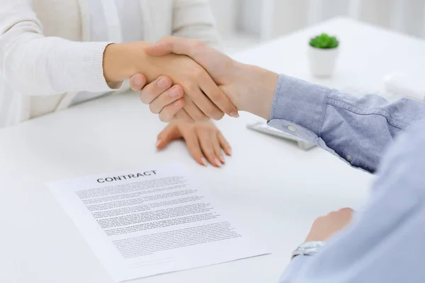 Zakenmensen schudden elkaar de hand bij ontmoetingen of onderhandelingen na contractbesprekingen. Zakenman en vrouw handdruk op kantoor terwijl ze aan het bureau zitten. Succesconcept — Stockfoto