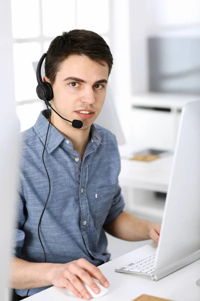 Group of operators at work. Call center. Focus on young man receptionist in headset at customer service. Business concept and casual clothing style — Stock Photo, Image