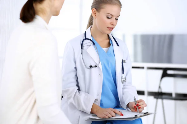 Doctor and patient during consultation. Physician at work filling up medication history record while sitting in emergency hospital, portrait shoot. Medicine and health care concept — Stock Photo, Image