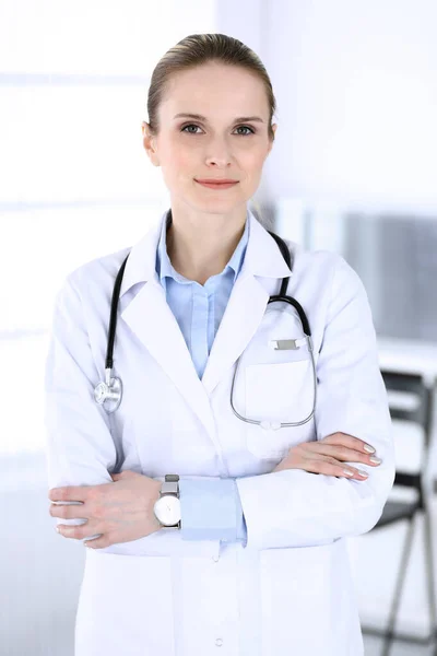 Dottoressa donna colpita alla testa al lavoro in ospedale. Medico in piedi dritto e sorridente, ritratto in studio. Medicina e concetto di assistenza sanitaria — Foto Stock