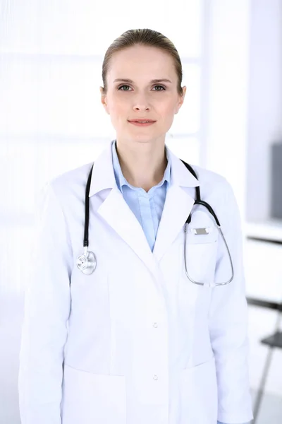 Una doctora disparando en el trabajo en el hospital. Médico de pie recto y sonriente, retrato de estudio. Concepto de medicina y salud — Foto de Stock