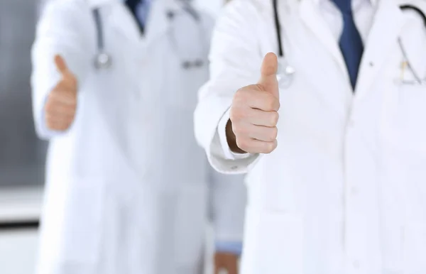 Группа современных врачей, стоящих в команде с большими пальцами вверх или ОК знак в больничном офисе, крупным планом. Врачи готовы осмотреть и помочь пациентам. Медицинская помощь, страхование в здравоохранении, лучшее лечение — стоковое фото