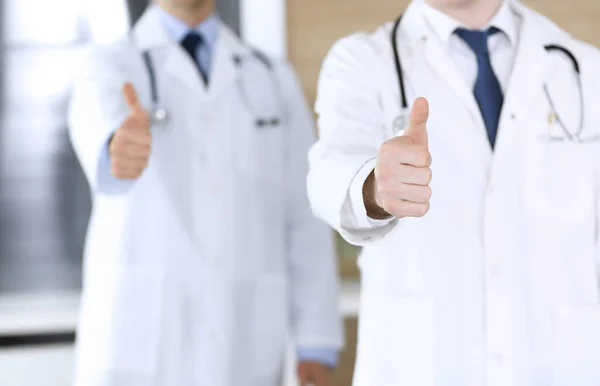 Modern orvosok csoportja áll, mint egy csapat hüvelykujj fel vagy Ok jel a kórházi irodában, közelkép. Az orvosok készek megvizsgálni és segíteni a betegeken. Orvosi segítség, biztosítás az egészségügyben, legjobb kezelés — Stock Fotó