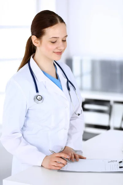 Läkarkvinnan på jobbet. Läkare eller intern student fyller upp medicinska dokument eller recept när du står på sjukhus receptionen. Uppgifter inom medicin och hälso- och sjukvård Stockfoto