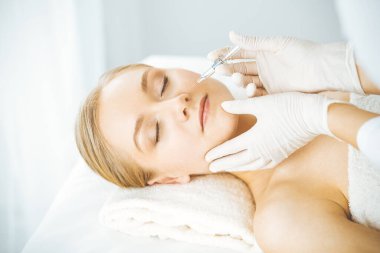 Güzellik doktoru sarışın kadın yüzüne şırıngayla güzellik prosedürü uyguluyor. Kozmetik tıp, güzellik enjeksiyonu konsepti