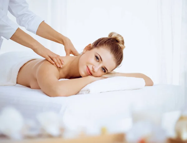 Mujer joven y rubia disfrutando del masaje de espalda en el salón de spa. Concepto de belleza — Foto de Stock
