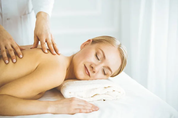 Hermosa mujer feliz disfrutando de masaje de espalda con los ojos cerrados. Concepto de salón de belleza y spa — Foto de Stock