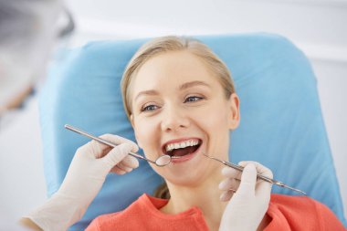 Gülümseyen beyaz kadın dişçi kliniğinde dişçi tarafından muayene ediliyor. Sağlıklı dişler ve ilaçlar, stomatoloji konsepti