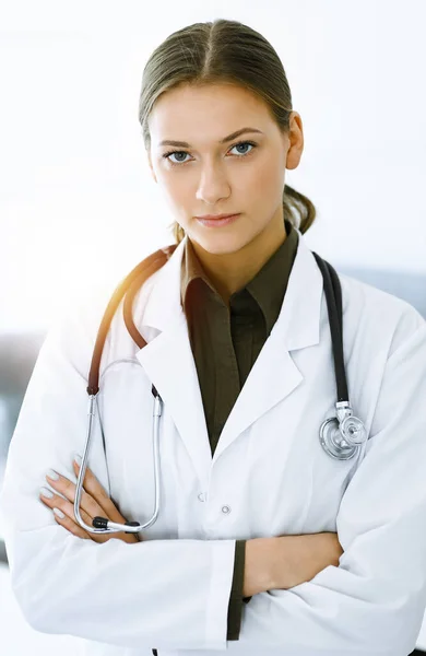 Mujer-médico de pie y mirando a la cámara en la clínica soleada. Un servicio médico perfecto. Medicina y asistencia sanitaria — Foto de Stock