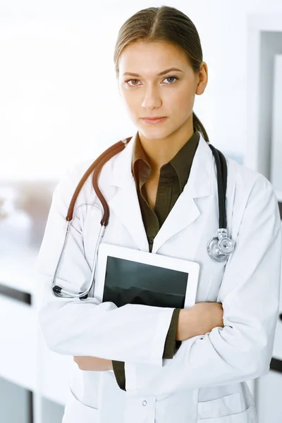 Donna-medico in piedi e guardando la macchina fotografica in clinica soleggiata. Servizio medico perfetto. Medicina e sanità — Foto Stock