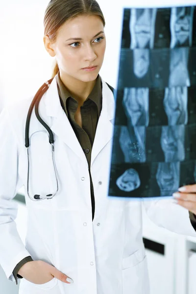 Orvos-nő röntgenképet vizsgál a kórházban. Sebész vagy ortopéd orvos a napsütéses klinikán. Orvosi és egészségügyi koncepció — Stock Fotó
