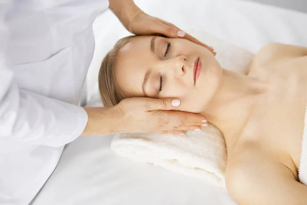 Güzel beyaz kadın spa salonunda gözleri kapalı yüz masajından zevk alıyor. Tıp ve Güzellik konseptinde rahatlatıcı tedavi — Stok fotoğraf
