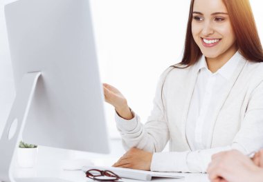 Güzel genç bayan güneşli ofiste bilgisayarla masada oturuyor. Görünüşe göre öğrenci kız ya da iş kadını sıradan giyinmiş bir adamla iletişim kuruyor.