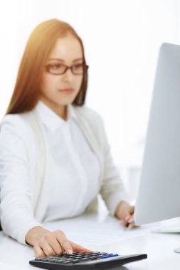 Muhasebeci hesap makinesiyle bakiyeyi kontrol ediyor, ellerinizi yakın tutun. Vergi ve denetim kavramları