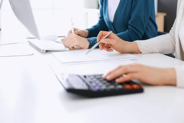 Contabilista verificando ficha financeira ou contando por calculadora de renda para a forma de imposto, mãos close-up. Mulher de negócios sentada e trabalhando com colega na mesa no escritório. Conceito de Fiscalidade e Auditoria — Fotografia de Stock