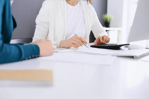 Contabilista verificando ficha financeira ou contando por calculadora de renda para a forma de imposto, mãos close-up. Mulher de negócios sentada e trabalhando com colega na mesa no escritório. Conceito de Fiscalidade e Auditoria — Fotografia de Stock