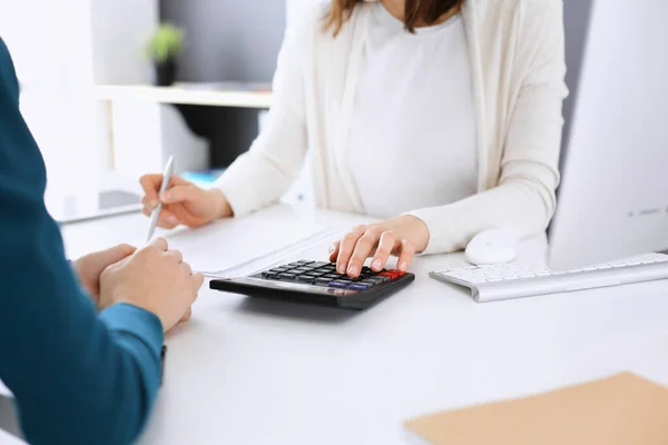 Contador que comprueba el estado financiero o cuenta por la renta de la calculadora para el formulario de impuestos, manos de cerca. Mujer de negocios sentada y trabajando con un colega en el escritorio de la oficina. Concepto fiscal y de auditoría —  Fotos de Stock