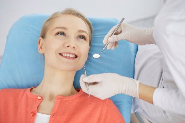 Gülümseyen beyaz kadın dişçi kliniğinde dişçi tarafından muayene ediliyor. Sağlıklı dişler ve ilaçlar, stomatoloji konsepti