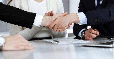 Modern ofiste iş adamları kontrat imzalandıktan sonra el sıkışıyor. Takım çalışması, ortaklık ve el sıkışma kavramı