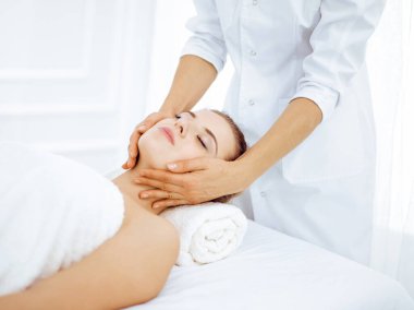Genç ve sarışın kadın spa salonunda yüz masajından zevk alıyor. Güzellik konsepti