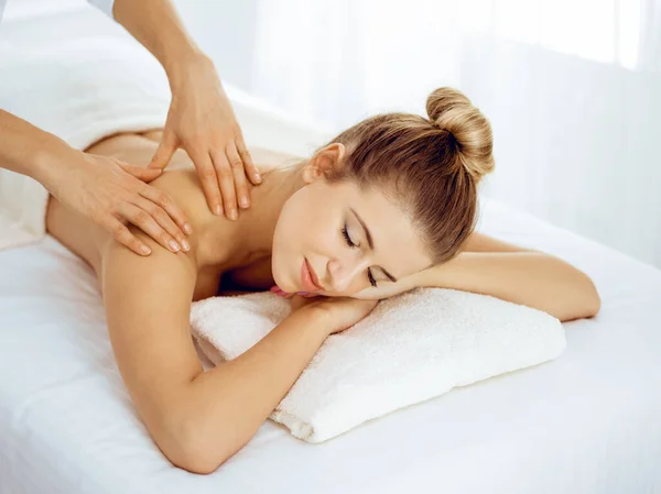 Ung och blond kvinna njuter av massage av tillbaka i spa salong. Skönhetsbegreppet — Stockfoto